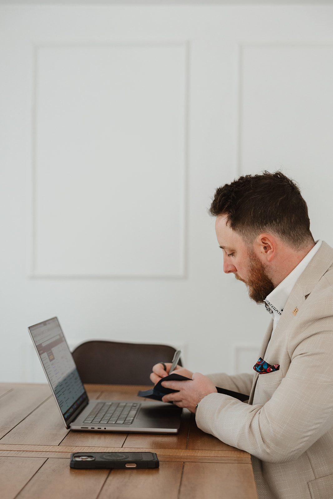 Founder writing notes beside laptop